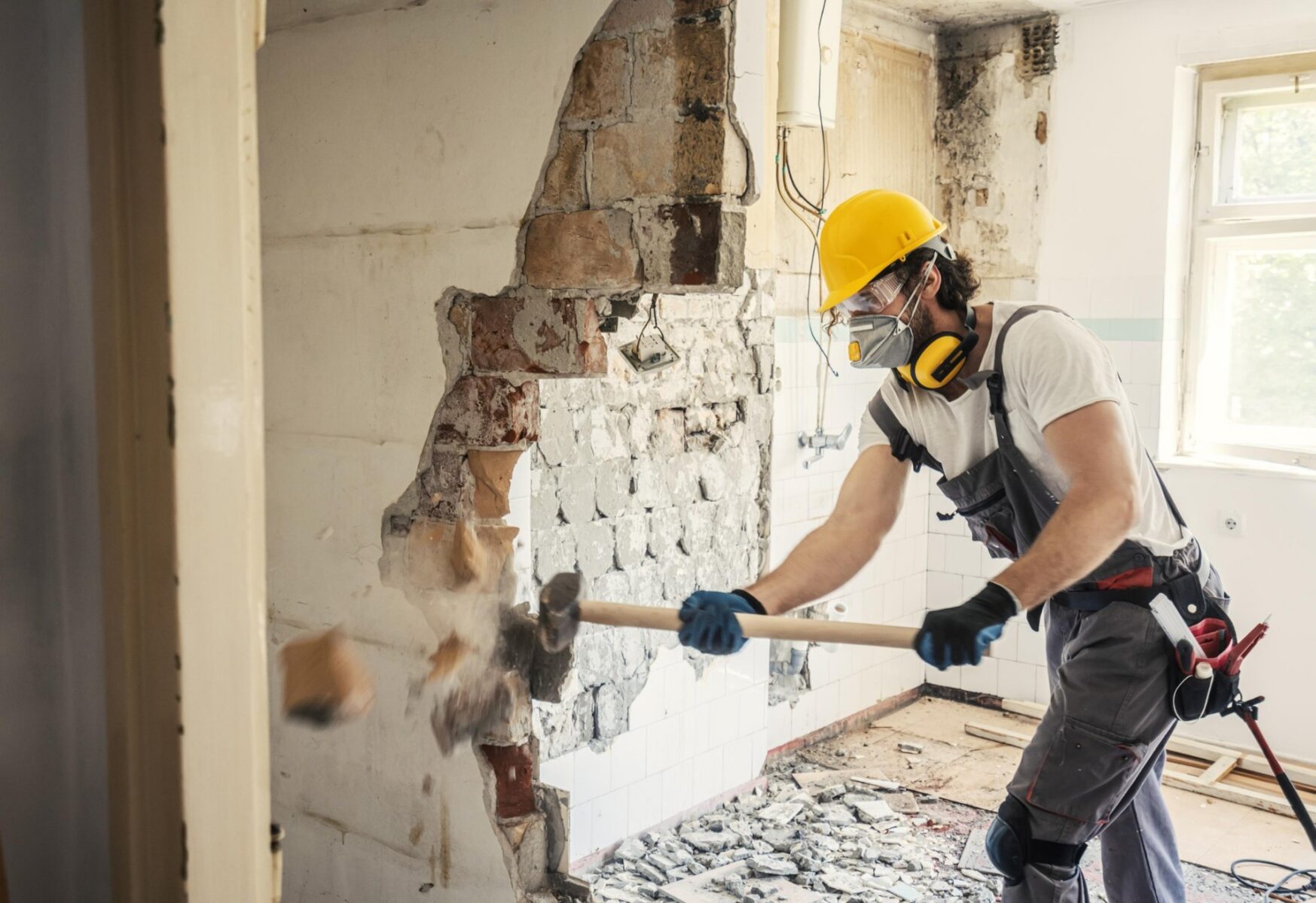 Worker removing internal wall finishes
